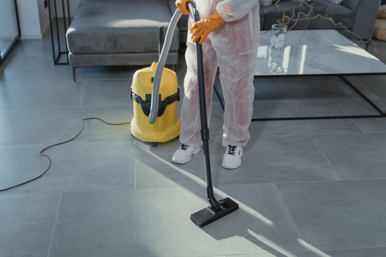 Mastering the First Impression: Your intriguing post title goes here A professional cleaner in protective gear vacuuming the floor in a modern living room.